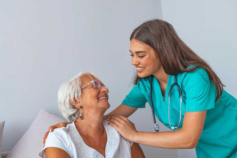 Family members and an older adult speak with a caregiver in a bright assisted living common area.
